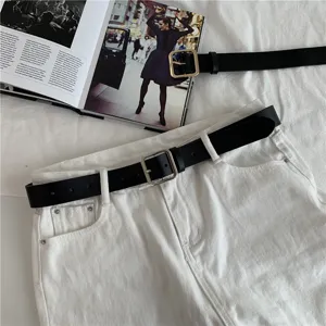 Close up detail of black leather belt featuring a classic metallic square buckle.