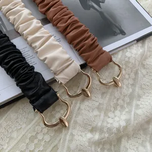 Primo piano di cinture elastiche arricciate con fibbie metalliche dorate su pizzo.