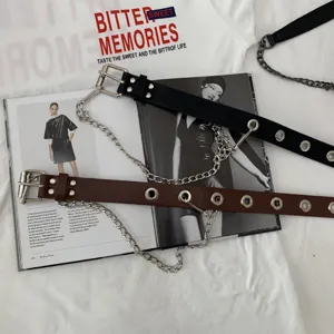 Detailed view of punk style women leather belt with metal eyelets and decorative chains.