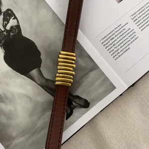 Cintura sottile in pelle vintage da donna con elegante decoro in barre di metallo dorato.