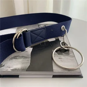 Canvas belt metal double ring detail shot, fashion cargo trouser accessory texture closeup.