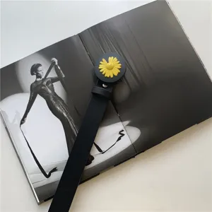 Detailansicht eines eleganten schwarzen Ledergürtels mit gelber Gänseblümchen-Schnalle.