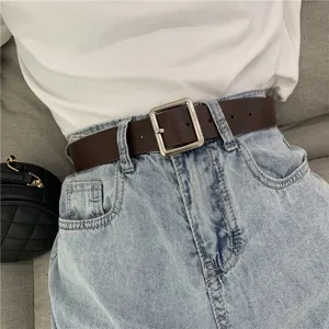 Detail shot of a minimalist dark brown leather belt with a sleek silver square buckle worn.