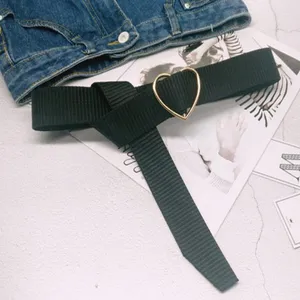 Black canvas belt with a stylish gold heart buckle, minimalist design for women fashion.
