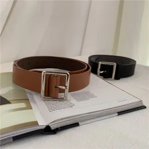 Close-up detail of stylish leather belt with square metal buckle placed on white background.