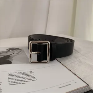 Close up view of minimalist black leather belt with silver square buckle detail.