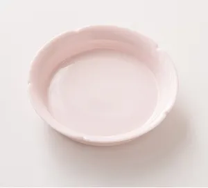 Detailed close-up of a charming light pink ceramic tea saucer with delicate flower rim.