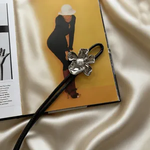 Close-up detail of a women fashion leather cord belt featuring a silver flower buckle and pearl accent.
