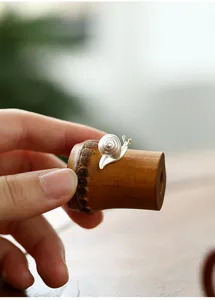 Detalle de soporte para tapa de tetera de bambú artesanal con lindo caracol de plata.