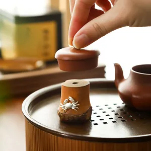 Soporte artesanal de raíz de bambú natural para tapa de tetera con cangrejo plateado.