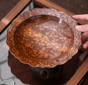 Detail van de keramische theepotlegger met bruine spetterglazuur en geschulpte bloemrand.
