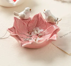 Pink ceramic lotus jewelry dish detail, cute bird ring holder for desktop accessory storage.