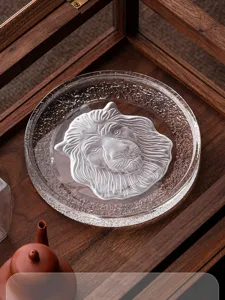 Nahaufnahme einer klaren Kristallglas-Teekannenmatte mit einem mattierten Löwen-Relief.
