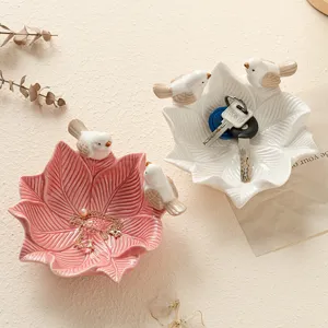 Ceramic leaf-shaped storage tray with cute bird decor, ideal for jewelry and keys organization.
