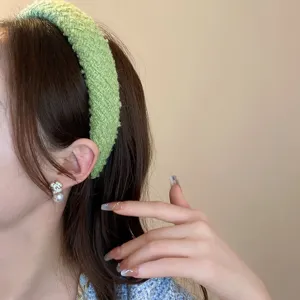 Primo piano della fascia per capelli in tessuto verde indossata con un elegante orecchino.