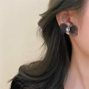Gros plan détaillé de l'élégante boucle d'oreille nœud en filet noir portée à l'oreille.