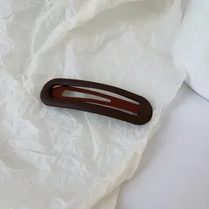 Détail de pince à cheveux snap marron foncé mat, barrette minimaliste pour coiffure chic.