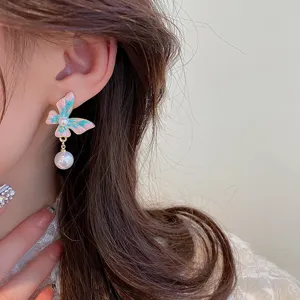 Detailed close-up view of a chic butterfly pearl drop earring worn gracefully on the ear.