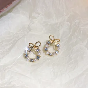 Detailed close-up view of elegant bow pearl rhinestone stud earrings with gold finish.