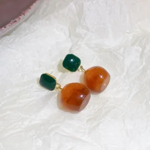 Detailed view of stylish green square and amber drop dangle earrings, elegant jewelry piece.