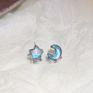 Close-up detail of asymmetric star and moon earrings with holographic finish and pearls.