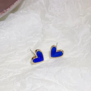 Blue heart stud earrings detail shot, minimalist metal rim design with brilliant blue finish.