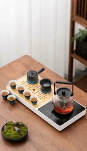 Set da tè kung fu automatico domestico con bollitore in vetro, vassoio in legno e tazze in ceramica.