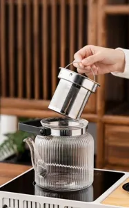 Dettaglio teiera in vetro con infusore in acciaio inossidabile e corpo scanalato per tè.
