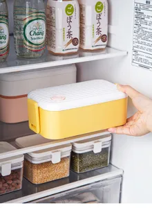 Double layer plastic bento lunch box in yellow and white, detail view in refrigerator.