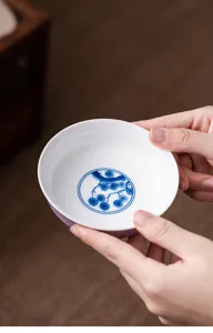 Detailed close-up of ceramic tea cup holder featuring hand-painted blue and white pine motif.