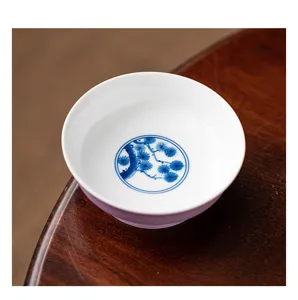 Ceramic tea cup saucer detail, hand-painted blue and white pine design on purple pottery.