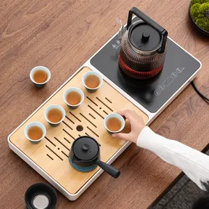 Set per tè elettrico automatico con bollitore in vetro, teiera e vassoio in legno.