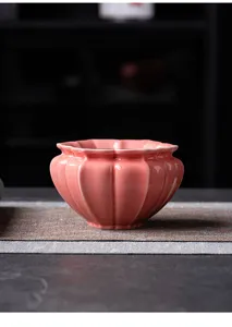 Detalle del elegante cuenco de cerámica rosa para residuos de té con borde de pétalos de flor.