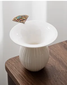 Ceramic tea strainer detail close-up showcasing elegant white funnel design and fan handle.