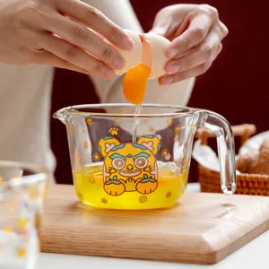 Clear glass measuring cup with cute tiger pattern, scale, and handle for kitchen baking use.