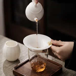 Elegant white ceramic tea strainer with golden handle for loose leaf tea brewing infusion.