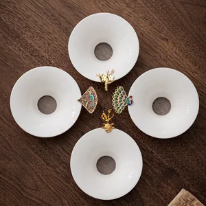 White ceramic tea strainer set with decorative metal handles for loose leaf tea brewing.