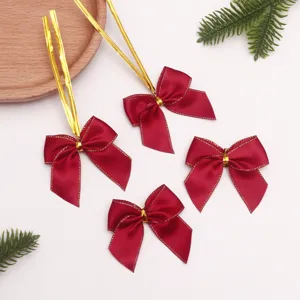 Vista detallada de lazos navideños rojos de poliéster con bordes dorados para decoración.