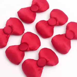 Détail de nœuds en tissu satiné rembourré rouge montrant une texture lisse et un bouton pour bricolage.