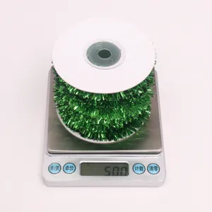 Detail view of shiny green metallic Christmas tinsel garland ribbon displayed on a digital scale.