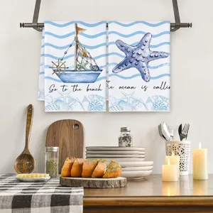 Detailed view of nautical beach theme kitchen dish towel with sailboat and starfish print.