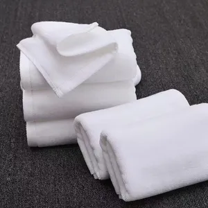 Soft white cotton towels detail view, neatly folded stack and rolls for hotel and bath use.