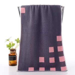 Detailed view of dark grey cotton face towel featuring stylish pink square geometric patterns.