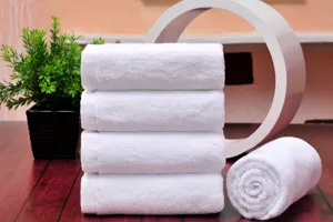 White cotton towel detail shot showing soft texture and neat folds for hotel bathroom use.