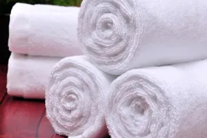 White cotton rolled towels set, soft and absorbent fabric texture, ideal for hotel and spa use.