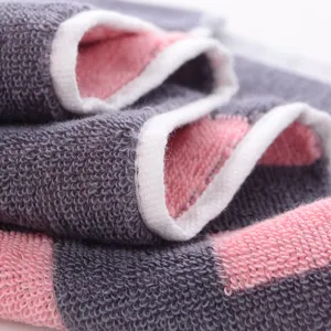 Close-up detail of pure cotton towel fabric showing soft plush loops and neat white edge binding.