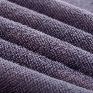 Close-up view of soft cotton towel terry texture showing dense grey-purple fabric loops.