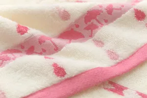 Detailed close-up view of soft cotton towel featuring pink umbrella jacquard texture.