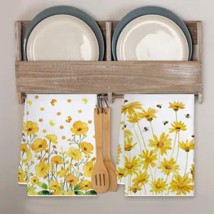 Detailansicht eines Küchentuchs mit Sonnenblumen-Bienen-Druck an Holz-Wandhalterung.