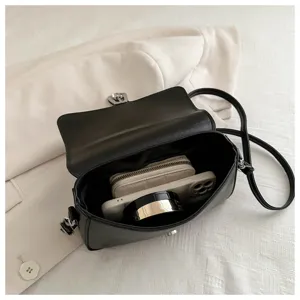 Black crossbody bag detail showcasing interior capacity with wallet and phone for daily use.